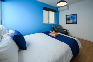 宇流麻的住宿－海まで徒歩1分 浜比嘉島まで車で10分 12名宿泊可能な宿泊施設 エムズハウス，蓝色的卧室设有白色的床铺和蓝色的墙壁