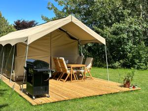 a tent with a table and chairs and a grill at Langø Feriecenter - Outdoor Lodge in Nakskov