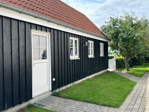 a black and white building with a white door at Langø Feriecenter - Sea View in Langø