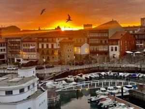 a city with boats in a marina at sunset at Las Rocas in Llanes