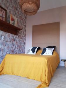 a bedroom with a yellow bed with two pillows at La Poussinière in Aiguèze