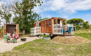 una pequeña casa de madera con una valla blanca en Dennis, en Goodwick