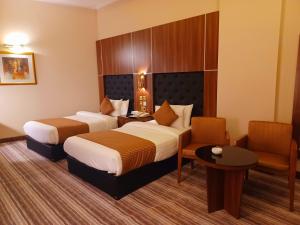 a hotel room with two beds and a chair at Royal Qatar Hotel in Doha