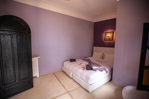 a bedroom with a white bed with purple walls at Riad RIM in Marrakesh