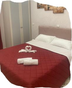 Una cama roja con dos toallas y un corazón. en la casetta del borgo, en Campomarino