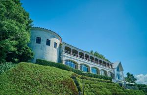 un gran edificio con arbustos delante de él en 浜名湖オーベルジュ　キャトルセゾン, en Ōsaki