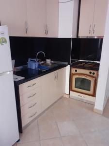 cocina con armarios blancos, fregadero y fogones en Beach apartment durres, en Durrës
