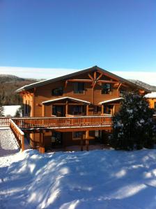a large wooden house in the snow with snow covered ground at Le Grand R in Saint-Donat-de-Montcalm
