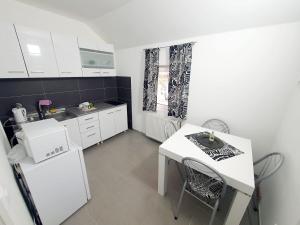 a kitchen with white appliances and a white table and chairs at Ispod duge in Dobroselica