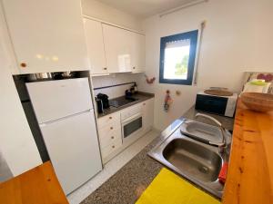 een keuken met een witte koelkast en een wastafel bij Apartament a Pals, amb piscina, platja a 1 minut in Pals