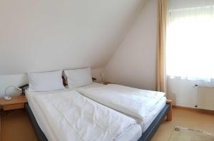 a bedroom with a bed with white sheets and a window at Urlaubslust Ferienhaus 16 in Trassenheide