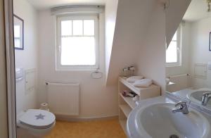 a white bathroom with a toilet and a sink at Urlaubslust Ferienhaus 16 in Trassenheide +26 photos