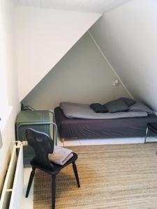 een slaapkamer met een bed en een stoel op zolder bij Villa med private værelser og delt køkken/badrum, centralt Viby sj in Viby