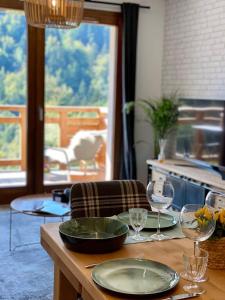 a table with two plates and wine glasses on it at Les Lucioles - Charming flat in the mountains in Saint-Jean-de-Sixt