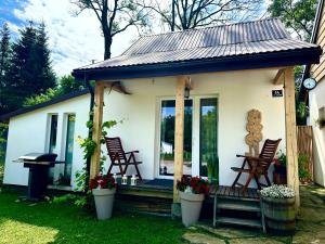 a small cottage with rocking chairs on a porch at Domek dla dwojga in Tylicz