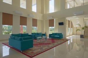 a large lobby with blue chairs and a rug at Liberta Hotel Grand Sayang Makassar in Makassar