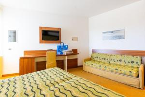 a bedroom with a bed and a desk and a table at Hotel Maregolf in Caorle
