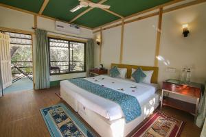 a bedroom with a large bed and a large window at Pench Wilderness Camp Resort in Khawāsa