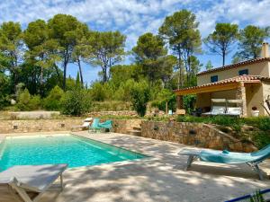 a swimming pool with two chairs and a house at Piscine chauffée, tennis, Mas provençal contemporain in Draguignan