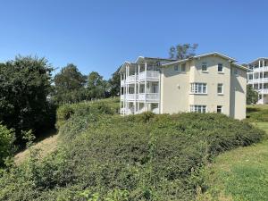 a large white house on a hill with bushes at Haus Greifswalder Bodden - FeWo 06 in Göhren