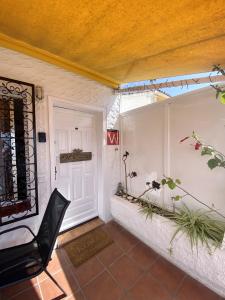 un porche con una silla negra y una puerta blanca en Guanche Bay, en Santa Cruz de Tenerife
