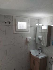 baño con lavabo y aseo y ventana en Studio με όλες τις ανέσεις, en Vétrina