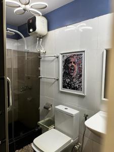 uma casa de banho com WC e uma pintura na parede em Charming one bedroom apartment 10 mins to the airport em Lagos