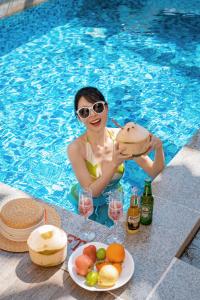 una mujer sentada en una piscina sosteniendo una bebida en JW Marriott Sanya Haitang Bay Resort & Spa en Sanya