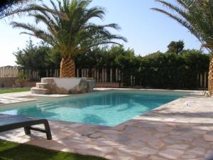 a swimming pool in a yard with palm trees at Modern Apartment in Valledoria with Swimming Pool in Codaruina