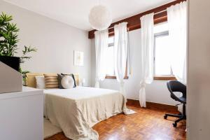 a white bedroom with a bed and a chair at VibesCoruna - Outeiro 222 in A Coruña