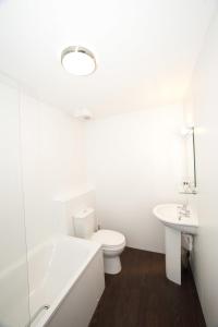 a white toilet sitting next to a bath tub at The Crown Inn in Stornoway