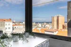 a view of a city from a window with potted plants at VibesCoruna - Outeiro 222 in A Coruña