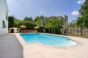einen Pool im Garten mit einem Tisch und Sonnenschirmen in der Unterkunft Belle villa au calme avec piscine in Antibes