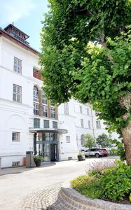 ein großes weißes Gebäude mit einem Baum davor in der Unterkunft Vejlsøhus Hotel and Conference Center in Silkeborg
