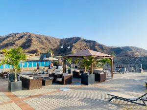 um resort com mesas e cadeiras e uma piscina em Fantastic Anfi Tauro Duplex with ocean view em Las Palmas de Gran Canaria