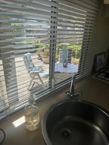 a sink and a window with a view of a deck at Gezellige STACARAVAN met groot, zonnig terras! in Belt-Schutsloot