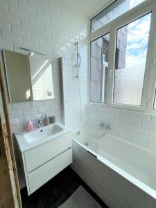 a white bathroom with a sink and a tub and a window at Tropical Dive, 2BDR Apartment in Antwerp