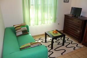 a living room with a green couch and a table at Apartments Stari Šibenik in Grebaštica