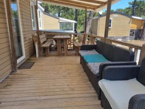 porche cubierto con sofás y mesa de picnic en Mobil Home 6 personnes Camping 5 étoiles, en Vendays-Montalivet