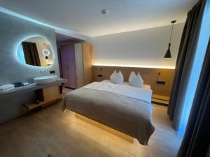 um quarto com uma cama, um lavatório e um espelho em Hotel Des Alpes em Selva di Val Gardena