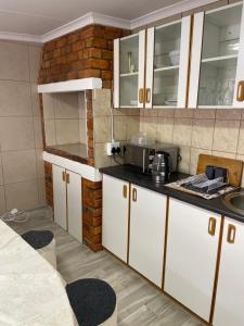 a kitchen with white cabinets and a brick wall at The Oasis Accommodation in Lüderitz