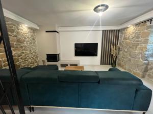a living room with a blue couch and a tv at Villa Copun with heated pool in Rab