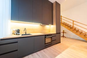a kitchen with black cabinets and a staircase at Apartamenty na Prusa in Mikołajki