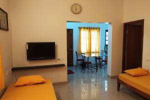 a living room with two beds and a flat screen tv at Athreyas@60/A in Mysore