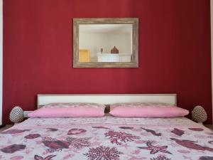 um quarto com uma parede vermelha com uma cama e um espelho em La Dimora di Helios em Noto