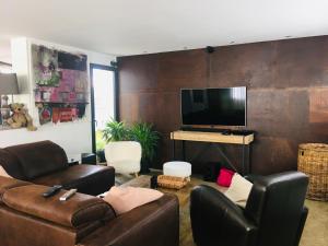 sala de estar con muebles de cuero y TV de pantalla plana en Bubble House, en La Rochelle