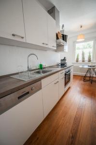 a kitchen with white cabinets and a wooden floor at 150qm LOFT, Tischtennis, Dart, Tischkicker in Hamburg