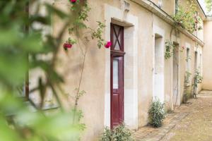 - un bâtiment avec une porte et des fleurs dans l'établissement La croix des vignes, à Brossay