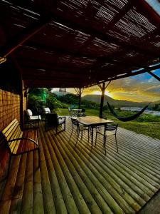 a wooden deck with a table and chairs and a hammock at Chambre Roucou vue Mont Pelée in Le Morne Rouge