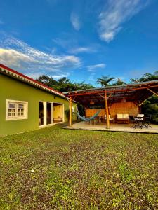 ein grünes Haus mit einer Terrasse mit einem Tisch und Stühlen in der Unterkunft Chambre Roucou vue Mont Pelée in Le Morne Rouge